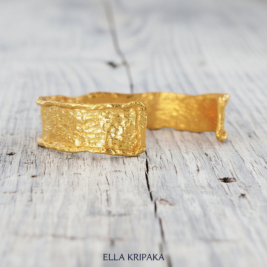 Hammered organic 24k 9999 gold uneven bracelet cuff on a wooden background, branding artist-jeweler name 'Ella Kripaka'