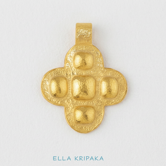 24k 9999 gold hammered Byzantine cross pendant with forged gold textures is on a white wooden surface, artist's name 'Ella Kripaka'