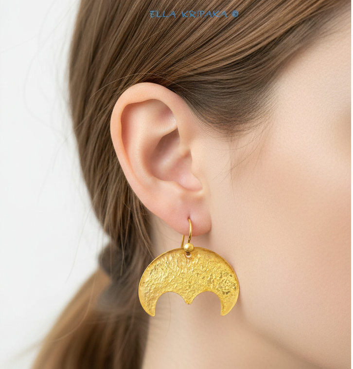 Hammered 24k 9999 Gold convex Moon earrings Ancient Rome style worn by a model on neutral on a white background, and artist-jeweler's name 'Ella Kripaka' branding