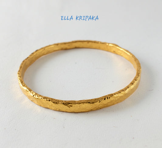 Organic hammered 24k 9999 Gold thick bangle uneven bracelet on a white background, artist's name 'Ella Kripaka' branding