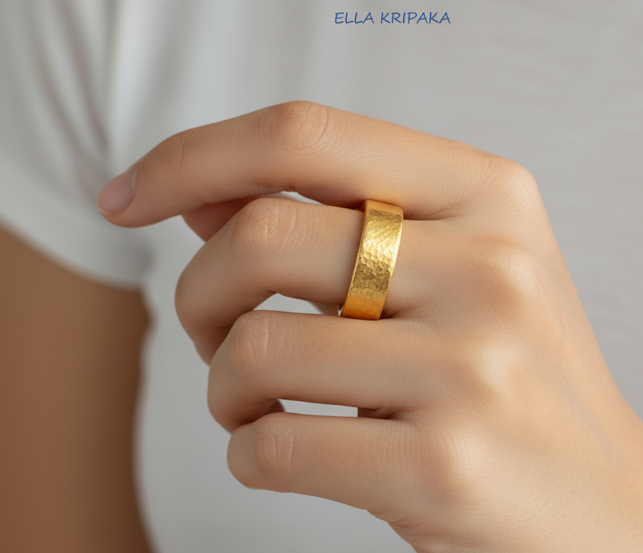 Hammered 24k 9999 Gold thick ring Ancient Rome style with a textured gold on person's finger on blurred white t-shirt backgroud, branded 'Ella Kripaka' artist-jeweler