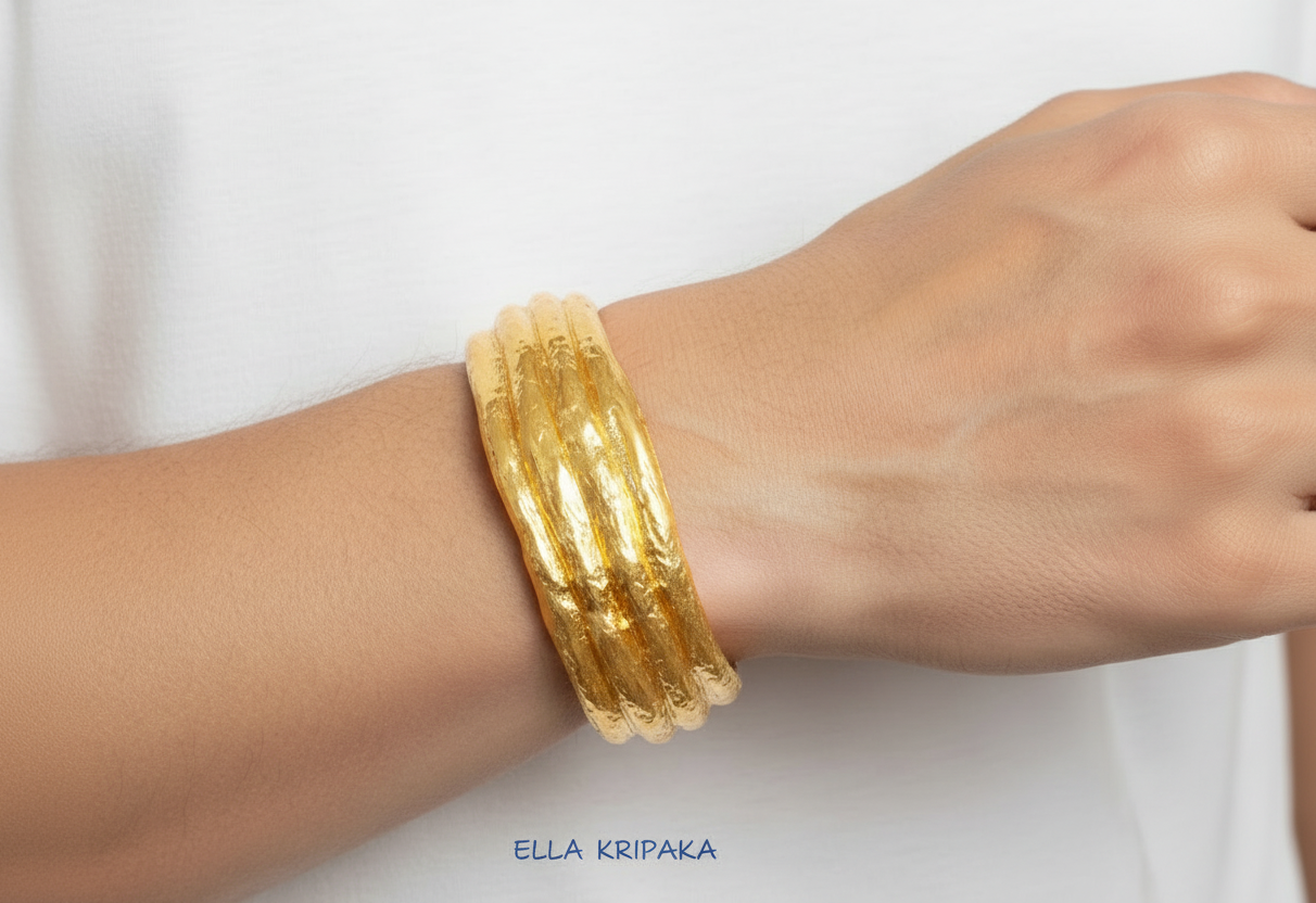 Organic 24k 9999 gold hammered uneven bracelet cuff worn on man's wrist with white t-shirt, indicating it is a custom-made jewelry with creator's name 'Ella Kripaka'