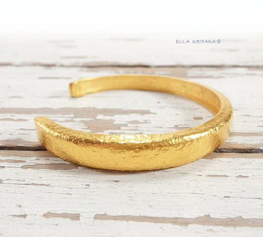Hammered 24k gold bracelet cuff Ancient Rome style on a old white wooden background, branding artist-jeweler name 'Ella Kripaka'
