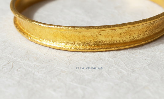 Hammered 24k gold bracelet textured cuff Ancient Rome style with durable folded edges on white rise paper surface, branding artist-jeweler 'Ella Kripaka'