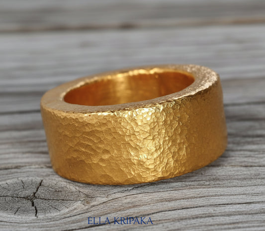 Hammered 24k Gold 9999 gold ring thick heavy and with textured surface on a grey wooden background, branded 'Ella Kripaka'