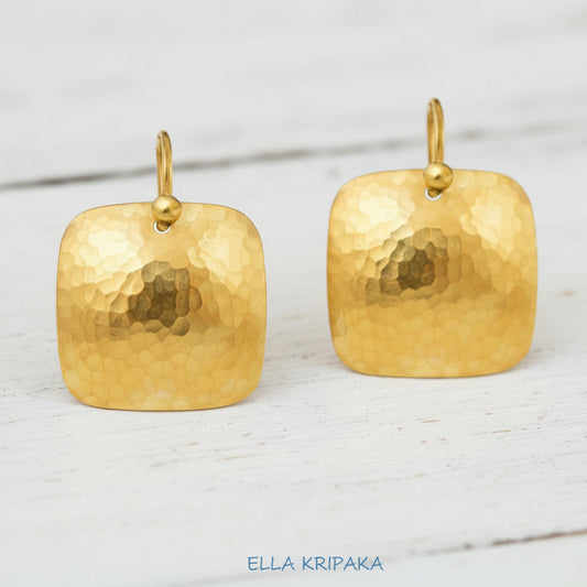 Hammered 24k 9999 Gold Byzantine square convex earrings on white wooden surface, artist-jeweler name 'Ella Kripaka'