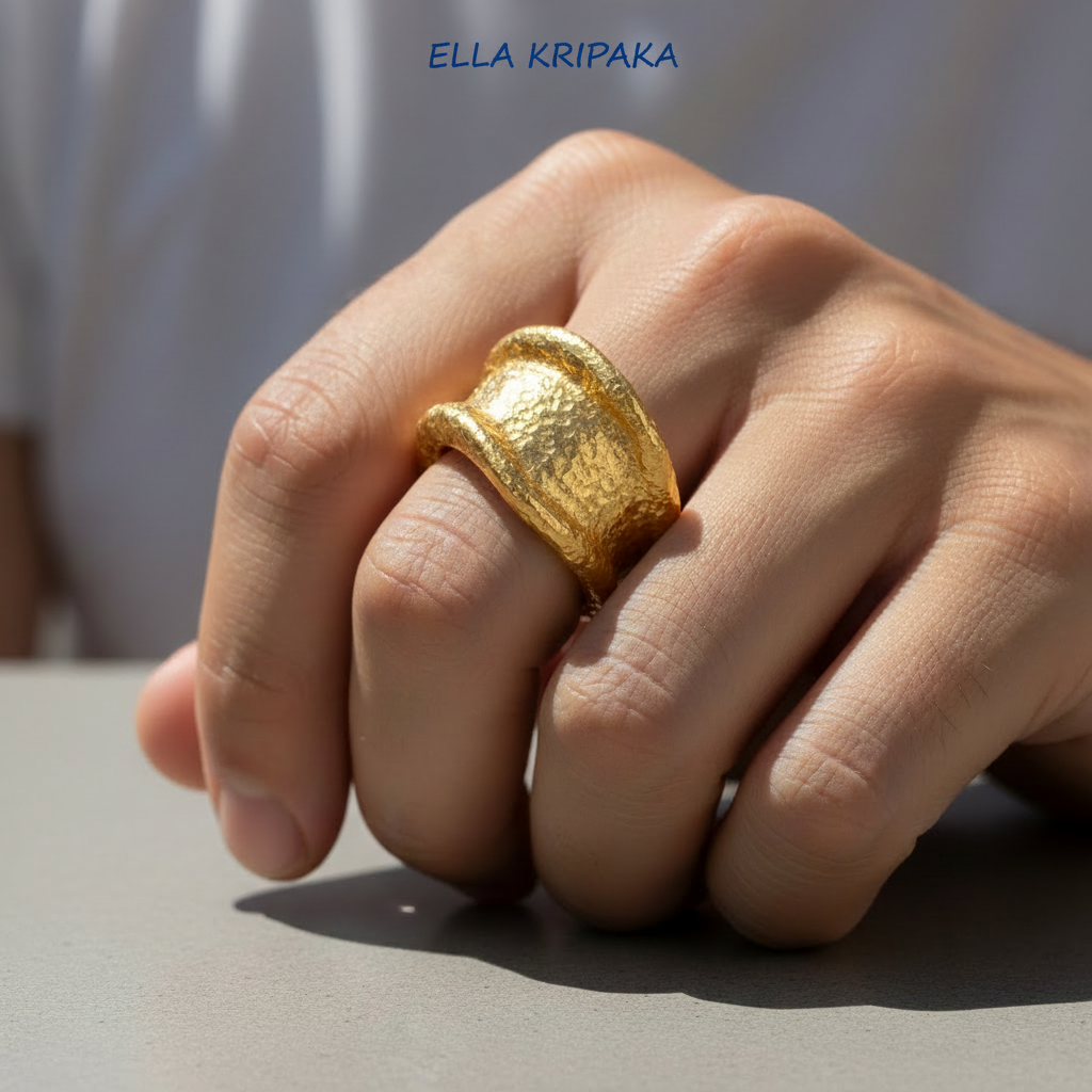 Organic hammered 24k 9999 gold ring signet with uneven thick edges is wearing on person's finger and on neutral surface, artist-jeweler's name 'Ella Kripaka' is written in picture
