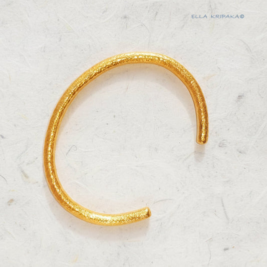 Hammered 24k 9999 gold rounded bracelet cuff Ancient Rome style on a white craft paper background, branding artist-jeweler name 'Ella Kripaka'