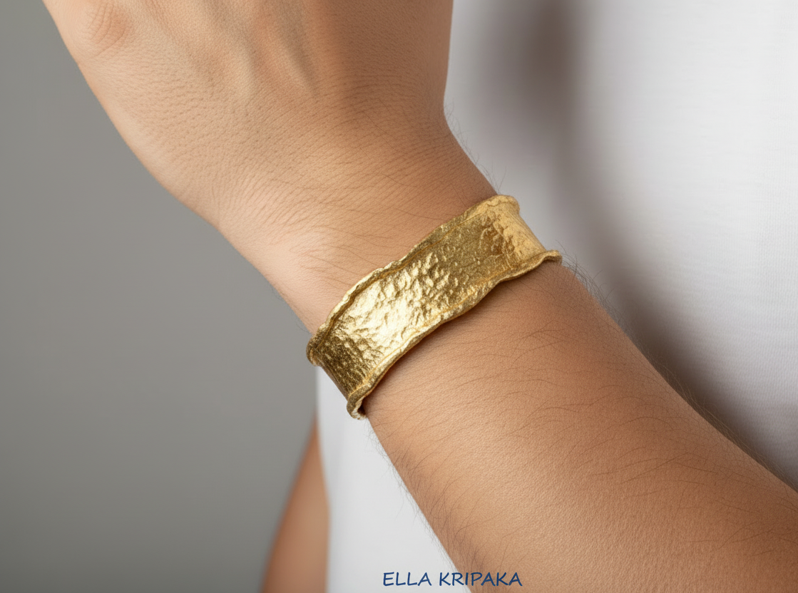 Organic hammered 24k 9999 gold bracelet uneven cuff worn on wrist by man on a white background, branding artist-jeweler name 'Ella Kripaka'