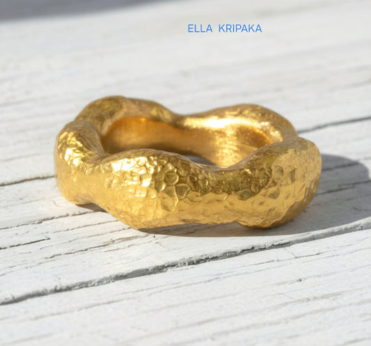 Hammered 24k 9999 Gold thick uneven wavy ring organic with textured gold on a white old wooden background, branded 'Ella Kripaka'