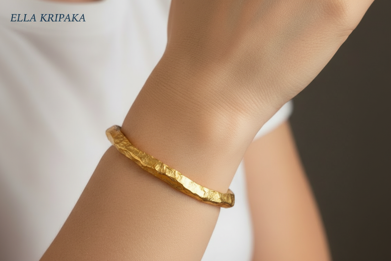 Organic hammered 24k 9999 Gold thick uneven cuff bracelet worn on woman's wrist and with white t-shirt and with 'Ella Kripaka' branding