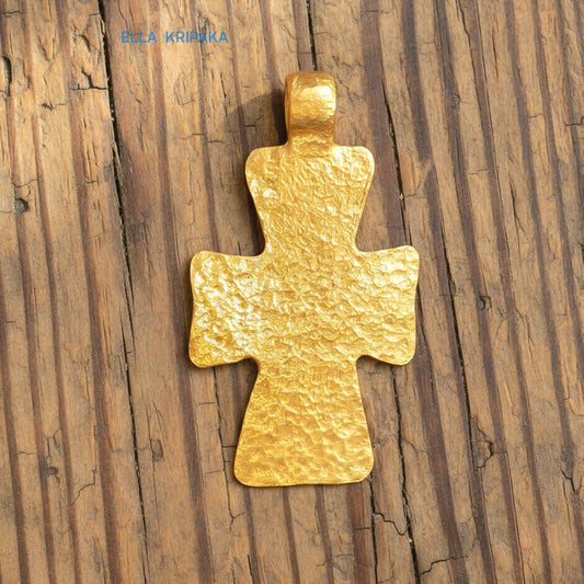Hammered 24k gold textured cross pendant on rustic old wooden surface, creator artist-jeweler 'Ella Kripaka' branding