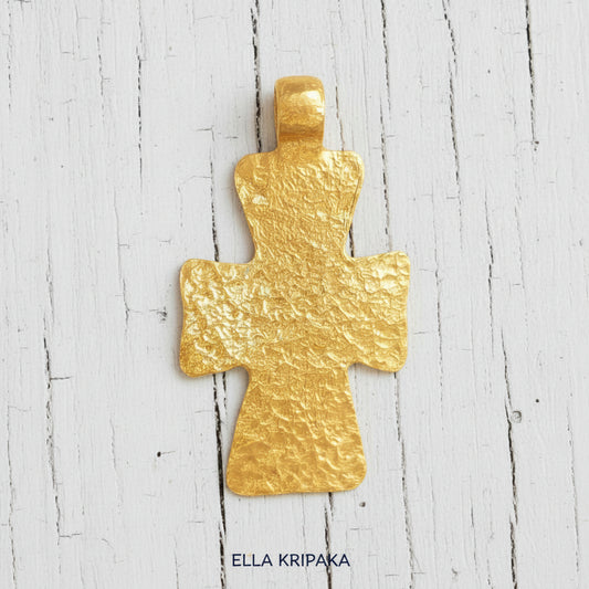 Hammered 24k gold textured cross pendant on rustic old wooden surface, creator artist-jeweler 'Ella Kripaka' branding