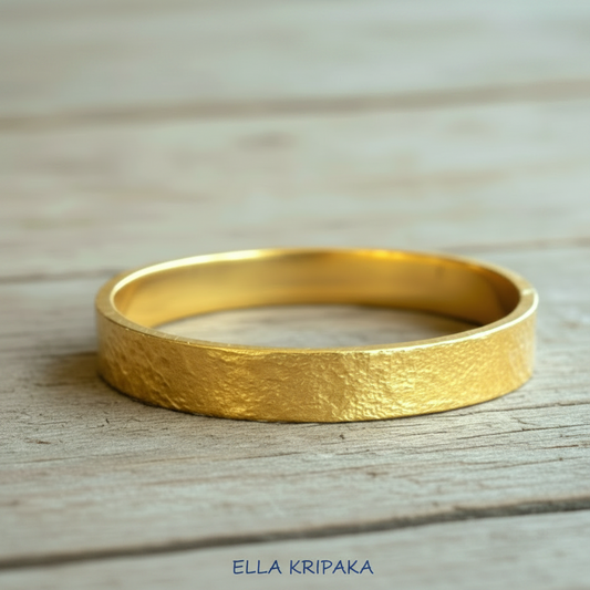 Hammered 24k Gold textured bangle shiny textured bracelet on light old wooden surface, artist's name 'Ella Kripaka' branding