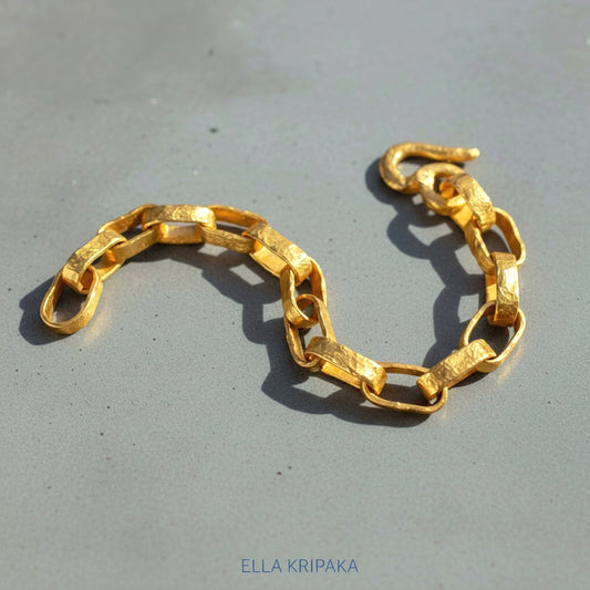 Hammered 24k 9999 gold chain thick bracelet with thick hook clasp Ancient Rome style on a grey background, artist-jeweler name 'Ella Kripaka' branding