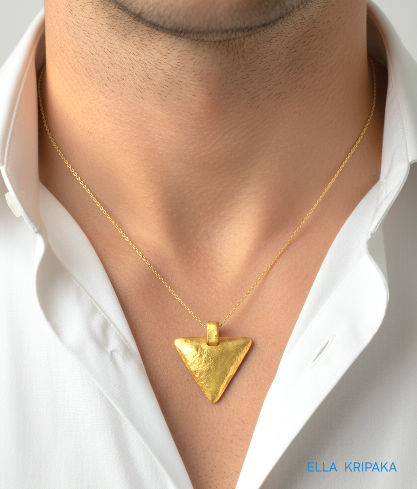 Hammered 24k gold convex triangle pendant with chain worn by a person and with a white shirt background with 'Ella Kripaka' branding
