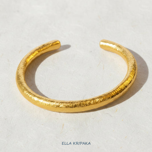 24k gold hammered rounded thick cuff bracelet on a white rise paper surface, branding artist 'Ella Kripaka'
