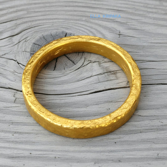 Hammered 24k gold thick ring on rustic wooden surface, artist-jeweler's name 'Ella Kripaka' is branded