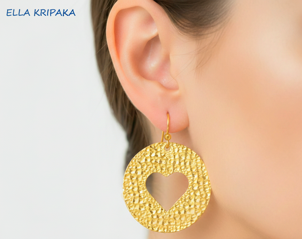 Organic 24k 9999 Gold hammered earrings with a heart cutout worn by a person, branded 'Ella Kripaka'