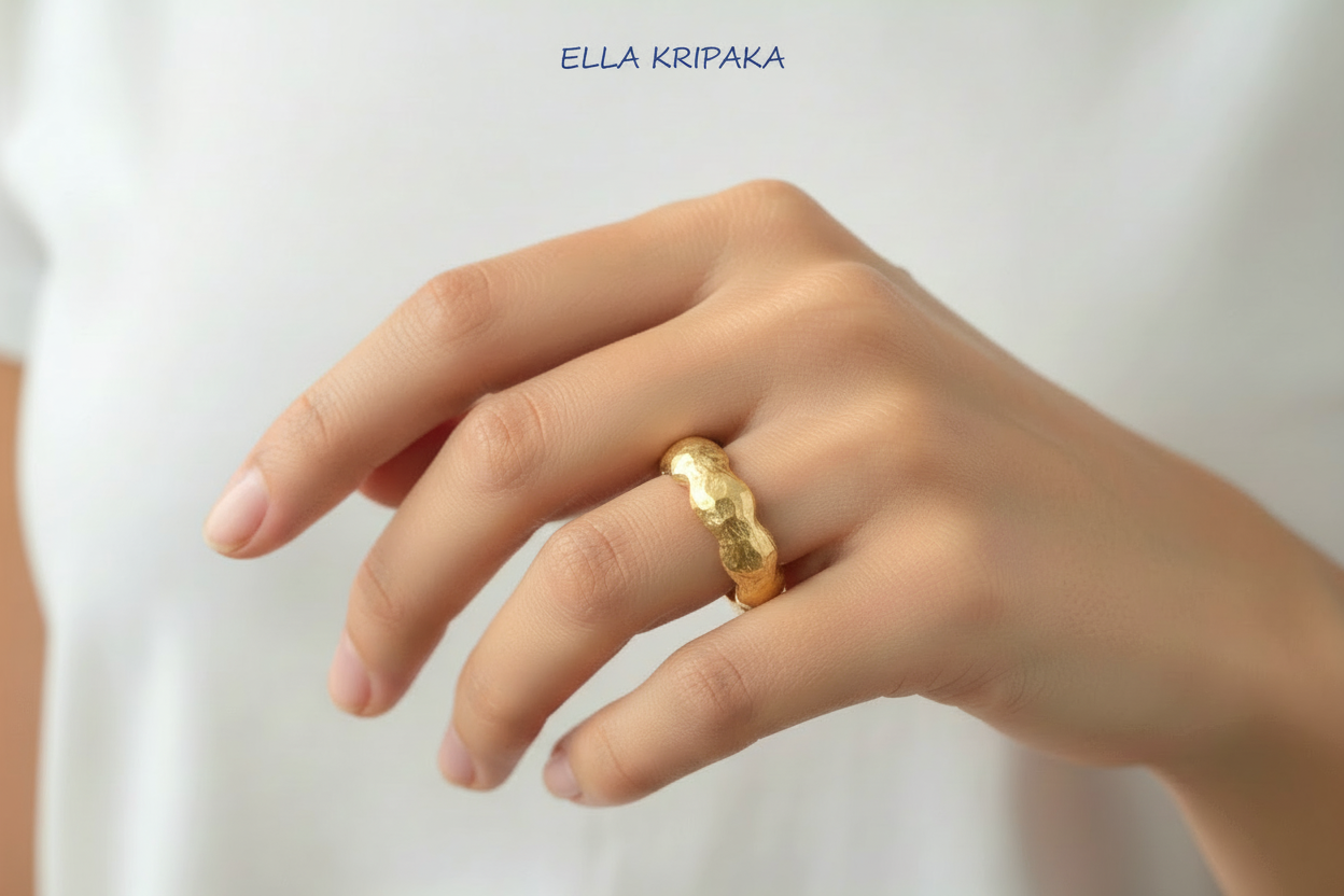 Organic hammered 24k 9999 Gold ring with wavy thick edges worn on person's finger and on a white background, artist-jeweler's name 'Ella Kripaka' is written in picture