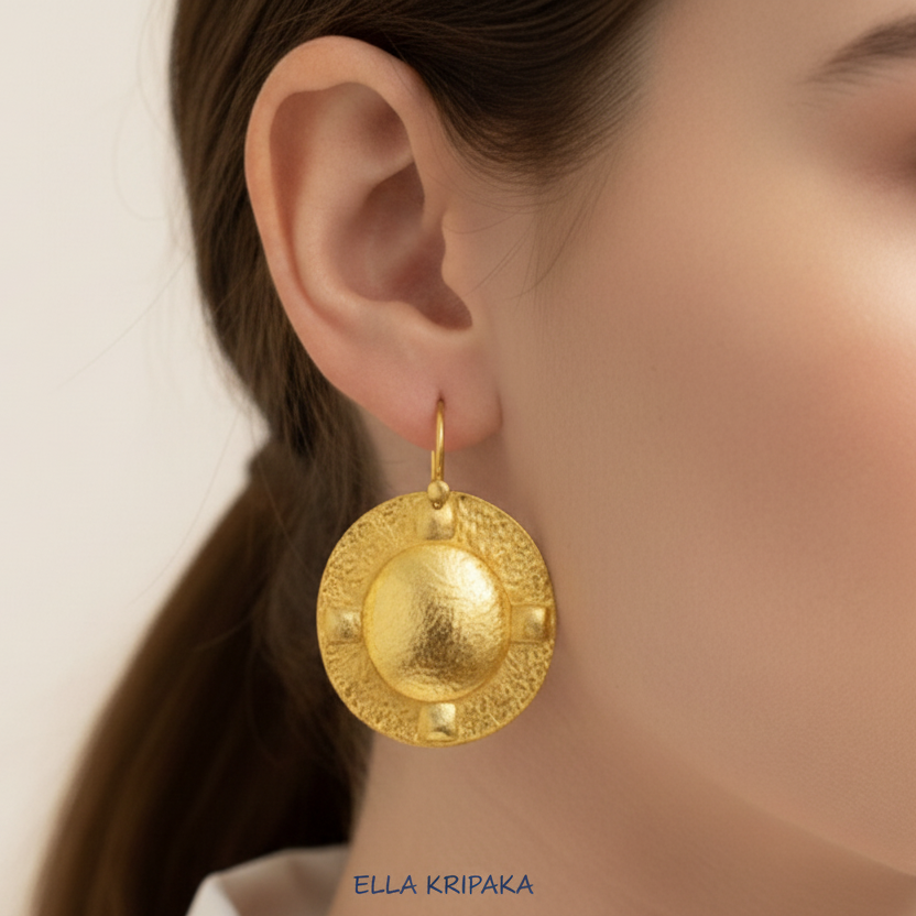 Hammered 24k 9999 Gold Byzantine oval convex earrings wearing by a person, and artist's name 'Ella Kripaka' branding