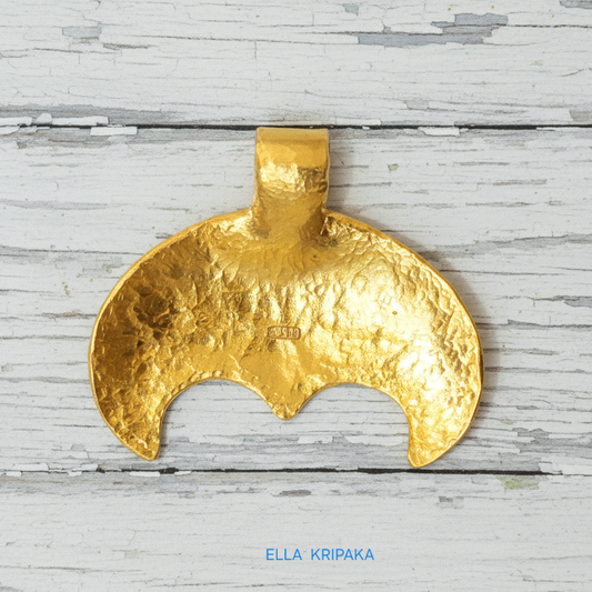Hammered 24k gold convex Moon pendant on a white rustic wooden background with 'Ella Kripaka' branding