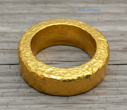 Hammered 24k 9999 Gold thick ring Ancient Rome style with a textured forged gold surface on a old wooden background, branded 'Ella Kripaka'