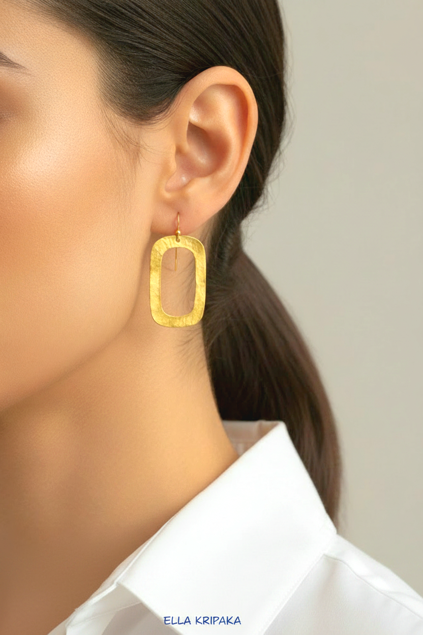 24k gold hammered textured rectangular hoops earrings worn by a woman and with white shirt and on light grey background, arist-jeweler 'Ella Kripaka' branding