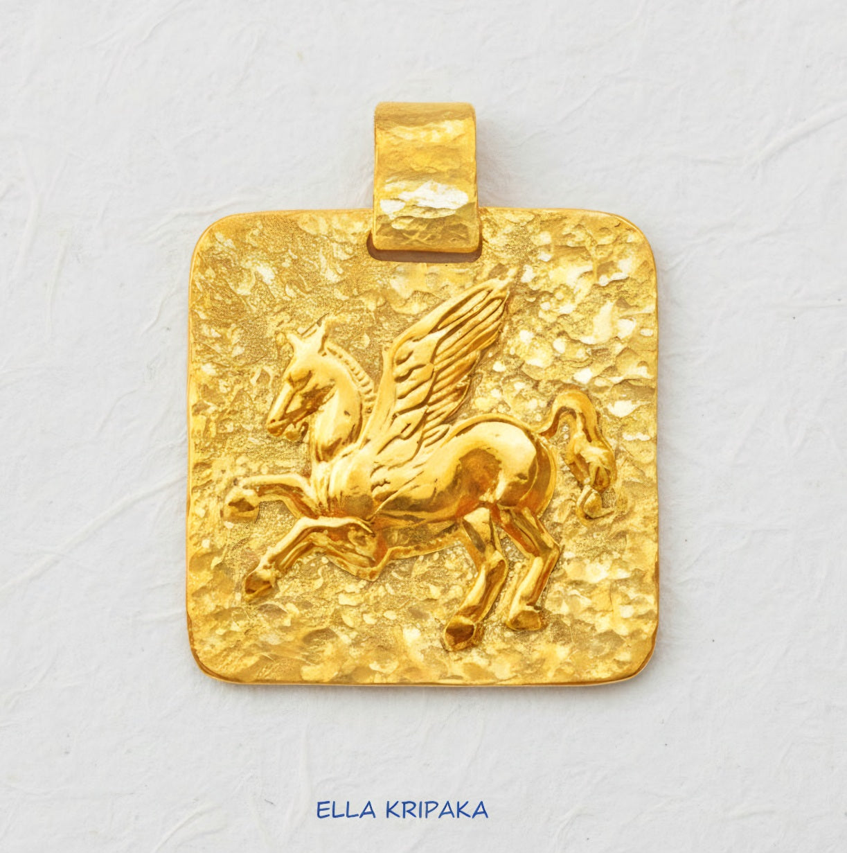 Hammered 24k Gold 9999 gold square pendant with convex Pegasus and with textured gold on white craft paper background, branded artist's name 'Ella Kripaka'