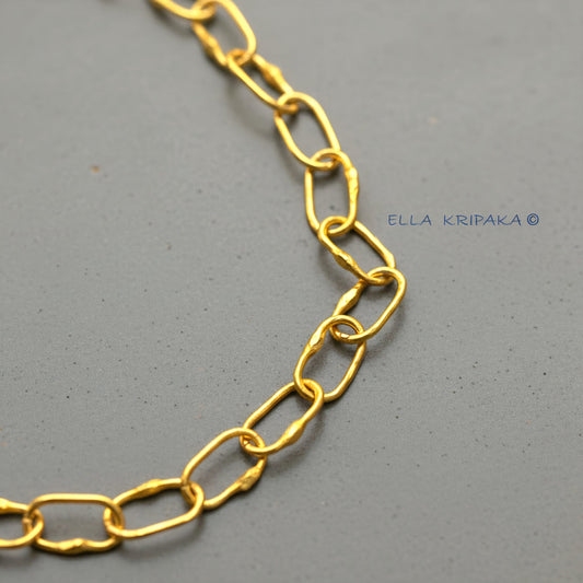 22k gold hammered chain on grey concrete background, artist-jeweler's name 'Ella Kripaka' branding