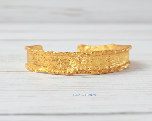 Hammered organic 24k 9999 gold uneven bracelet cuff  on a wooden background, branding artist-jeweler name 'Ella Kripaka'