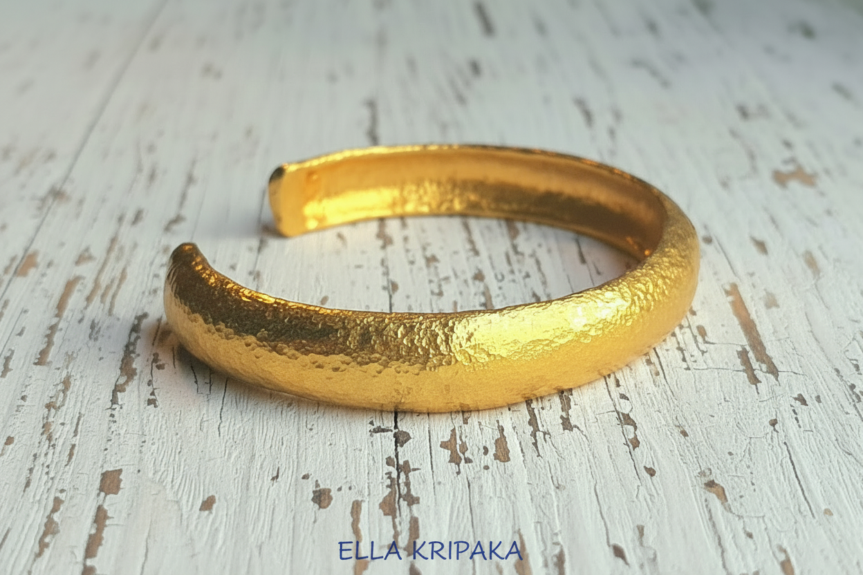 24k 9999 gold hammered Ancient Rome style bracelet cuff on old wooden background, indicating it is a custom-made jewelry with creator's name 'Ella Kripaka'