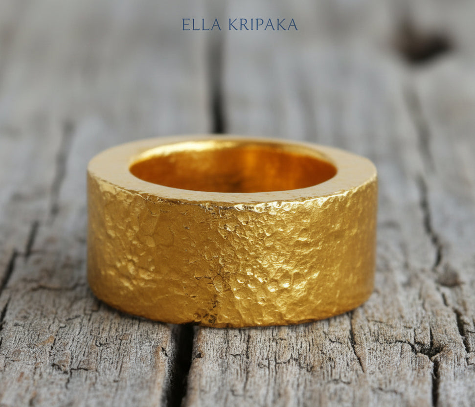 Hammered 24k Gold 9999 gold ring thick heavy and with textured surface on a grey wooden background, branded 'Ella Kripaka'