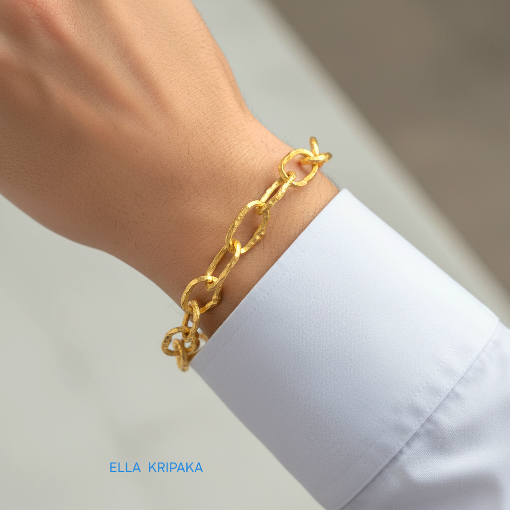 Hammered 24k gold organic bracelet chain with uneven textures is worn by a man on wrist and on blurred background, branding artist name 'Ella Kripaka'