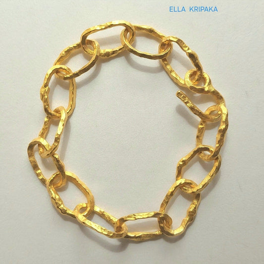 Hammered 24k gold organic bracelet chain with  uneven textures and a thick hook clasp on light beige paper surface, branding artist name 'Ella Kripaka'