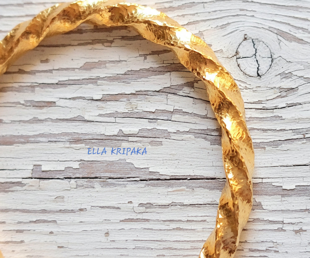 Twisted Viking Hammered 24k 9999 Gold bangle bracelet on white wooden surface, artist's name 'Ella Kripaka' branding