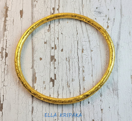 Hammered 24k 9999 gold bangle thick bracelet Ancient Rome style on old white wooden background, artist-jeweler's name 'Ella Kripaka'