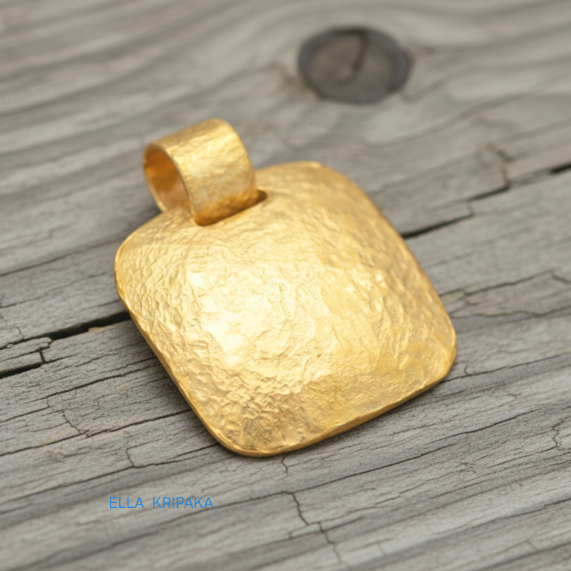 Hammered 24k gold textured convex square pendant on rustic wooden surface with 'Ella Kripaka' branding