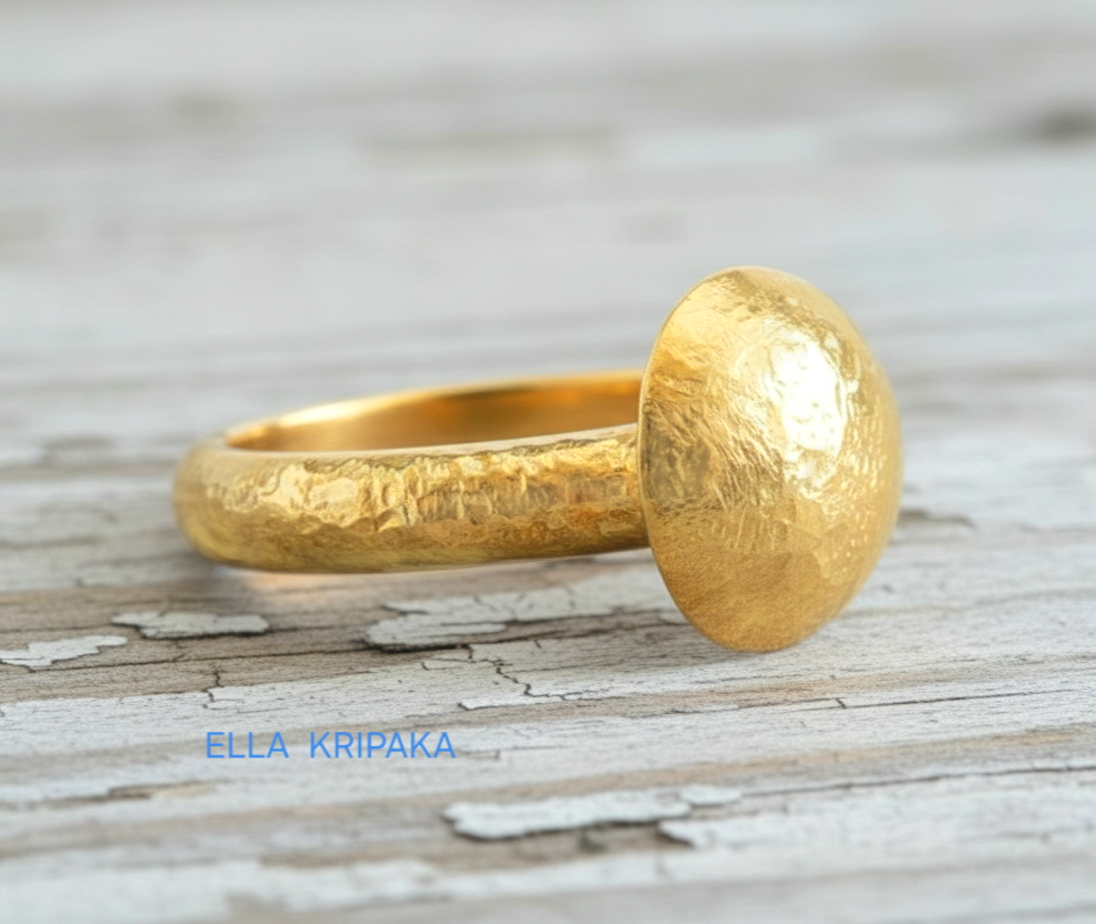 Hammered 24k 9999 Gold ring with convex disk signet Ancient Rome style and with forged textured gold on a white old wooden surface, artist-jeweler's name 'Ella Kripaka' branding