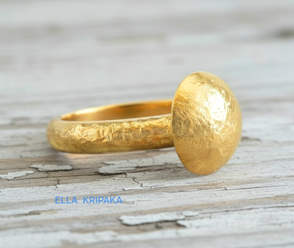 Hammered 24k 9999 Gold ring with convex disk signet Ancient Rome style and with forged textured gold on a white old wooden surface, artist-jeweler's name 'Ella Kripaka' branding