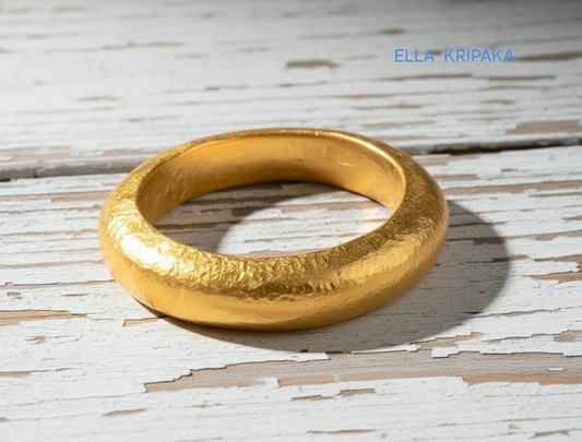 Hammered 24k 9999 Gold thick ring Ancient Rome style and with forged textured gold on a white old wooden surface, artist-jeweler's name 'Ella Kripaka' branding