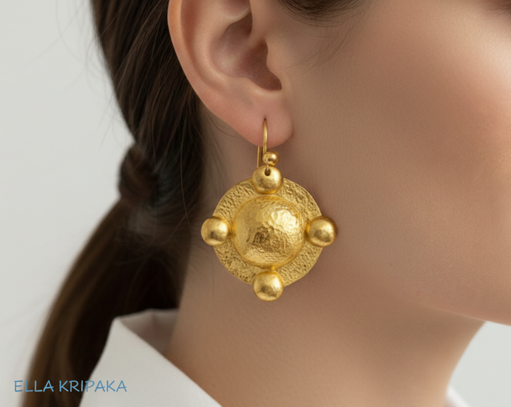 24k 9999 gold hammered Byzantine dome earrings with with shiny hammered gold textures is wearing on woman's ear, artist-jeweler's name 'Ella Kripaka'