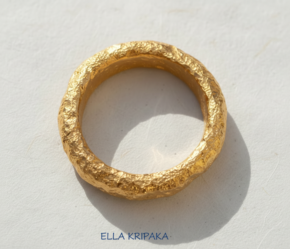 Organic hammered 24k 9999 Gold ring with thick edges on white paper surface, artist-jeweler's name 'Ella Kripaka' is written in picture