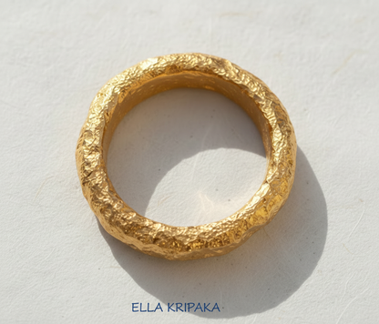 Organic hammered 24k 9999 Gold ring with thick edges on white paper surface, artist-jeweler's name 'Ella Kripaka' is written in picture