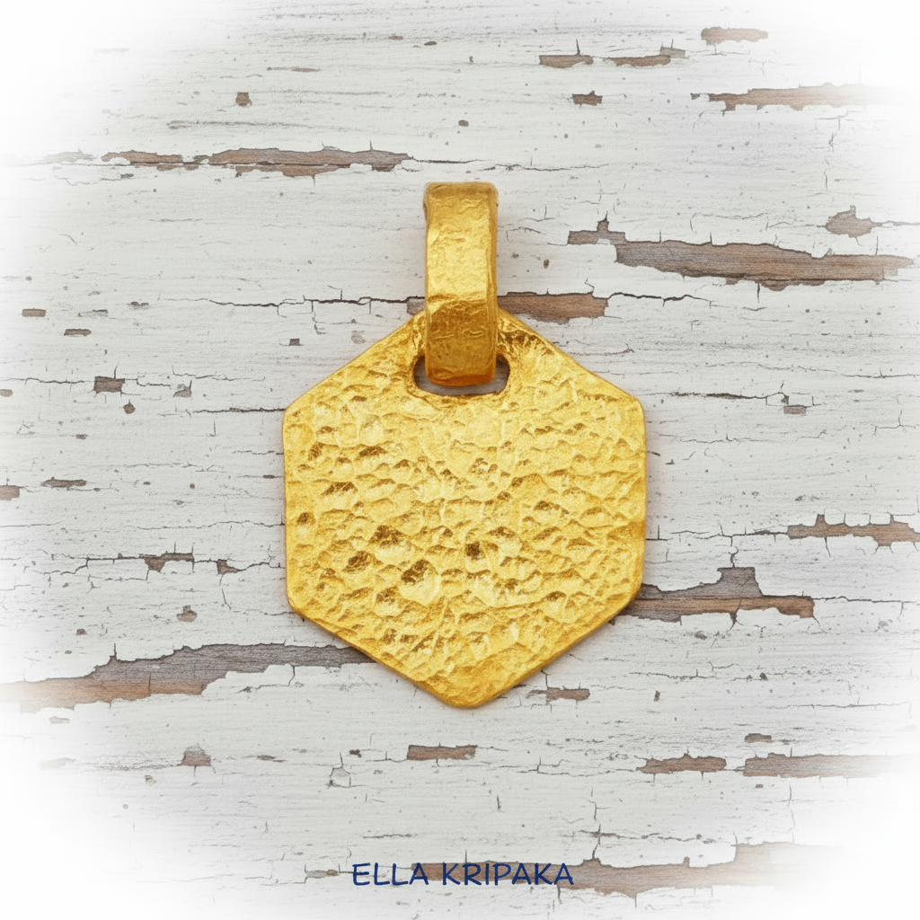 Hammered 24k gold, pure 9999 gold hexagon pendant with shiny forged gold textures on white old wooden surface, artist-jeweler 'Ella Kripaka' branding