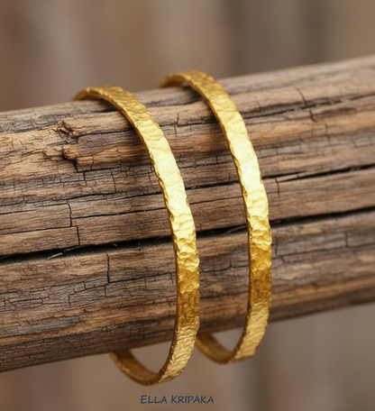 Organic hammered 24k 9999 Gold thick two bangles uneven bracelets on a rustic wooden thick stand, artist's name 'Ella Kripaka' branding