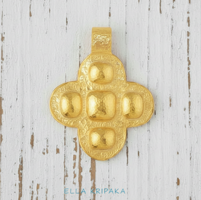 24k 9999 gold hammered Byzantine cross pendant with forged gold textures is on a white wooden surface, artist's name 'Ella Kripaka'
