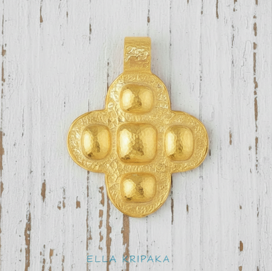 24k 9999 gold hammered Byzantine cross pendant with forged gold textures is on a white wooden surface, artist's name 'Ella Kripaka'