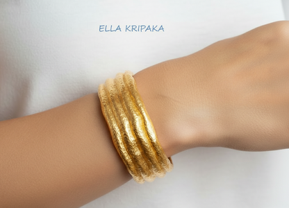 Organic hammered 24k 9999 Gold uneven cuff bracelet on a woman's wrist on white background, with artist's name 'Ella Kripaka' branding.