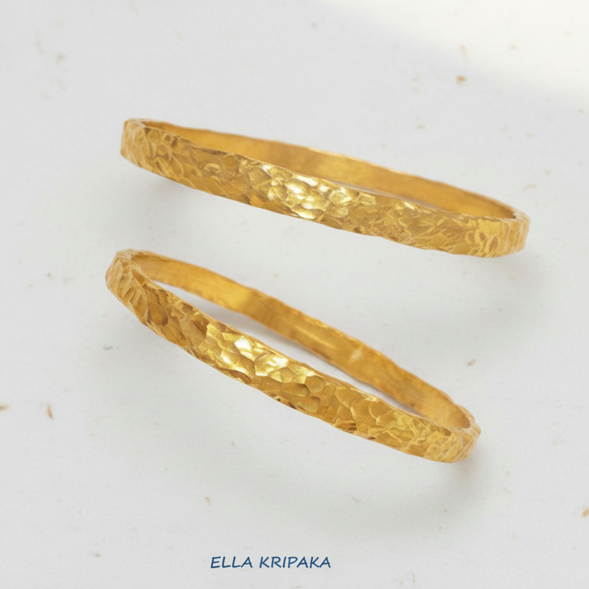 Organic hammered 24k 9999 Gold thick two bangles uneven bracelets on a white background, artist's name 'Ella Kripaka' branding